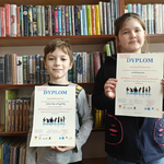 9 Dwoje dzieci z dyplomami w szkolnej bibliotece.png