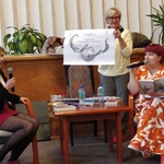 Ida Pierelotkin i Olga Gordiejew patrzą jak Iwona Pakuła prezentuje powiększoną ilustrację do książki Tajemne życie Magów (1)