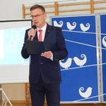 Andrzej Danieluk dyrektor szkoły na tle dekoracji mówi do mikrofonu
