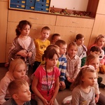 Dzieci z I b siedzą na podłodze patrzą w stronę teatrzyku.jpg
