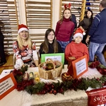 stoisko ze świecami Eleos i Caritas- nauczycielka z 2 uczniami.JPG