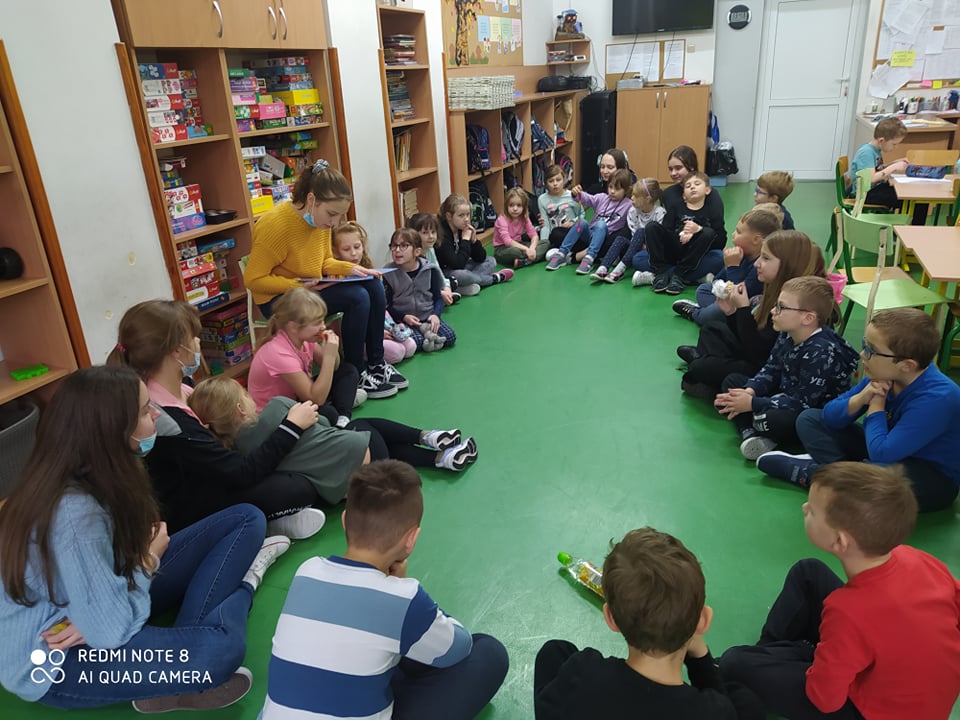 Dzieci siedzą w kole i słuchają opowiadania starszej koleżanki..jpg
