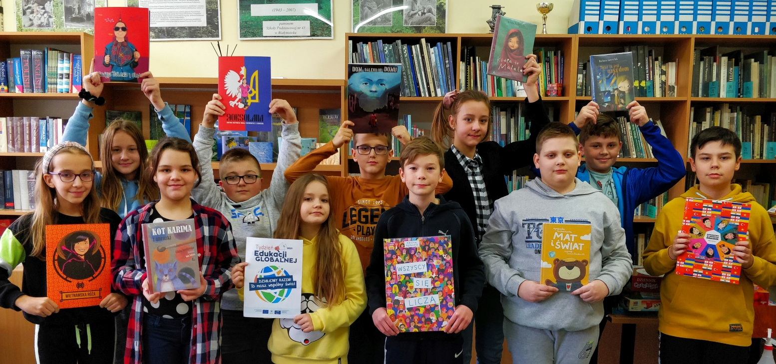 Dzieci z piątych klas trzymają książki omawiane na lekcji Dzieci świata i plakat TEGu.jpg