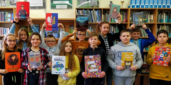 Dzieci z piątych klas trzymają książki omawiane na lekcji Dzieci świata i plakat TEGu.jpg
