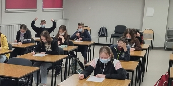 Grupa uczniów fotografowana z przodu - w ławkach piszą test wiedzy o Simonie Kossak (1).jpg