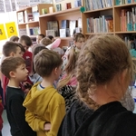 wystawa w czytelni - dzieci oglądają wystawkę z numerami gazetki  Szkoła na 102 (1).jpg