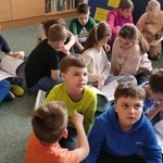 Dzieci siedzą na podłodze i oglądają archiwalne numery gazetki Szkoła na 102.jpg
