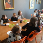 Dzieci siedzą przy stołach i słuchają przewodnika..JPG