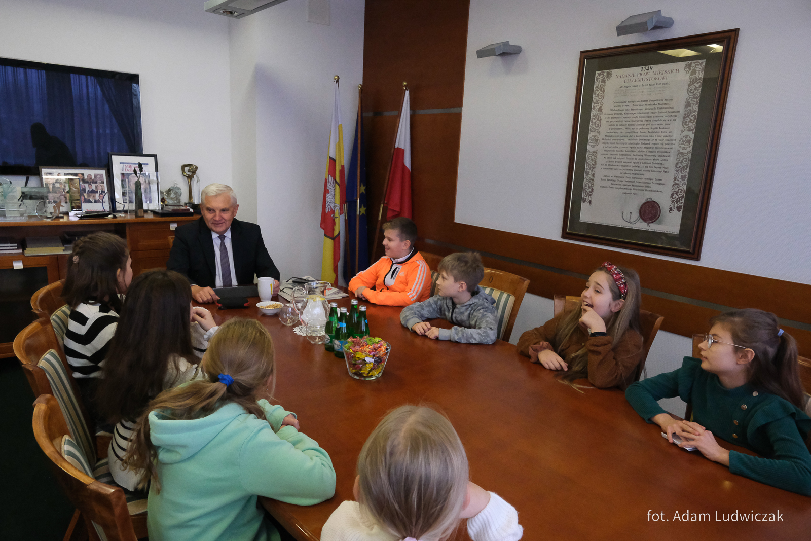 Dzieci siedzą przy stole z prezydentem miasta.jpg