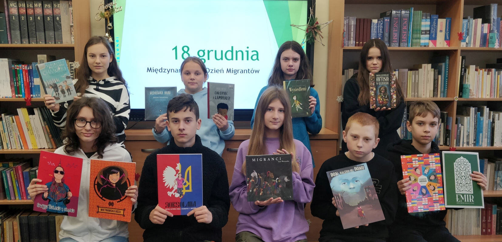 miniatura - uczniowie prezentujący książki z okazji Międzynarodowego Dnia Migrantów..jpg