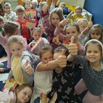 1a Dzieci z pierwszej klasy z kciukami podniesionymi w górę na znak Czytanie jest super.jpg
