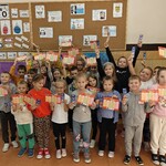 1e Pierwszoklasiści pod gazetką z okazji Ogólnopolskiego Dnia Głośnego Czytania.jpg