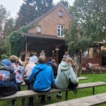 Uczniowie siedzą przed Leśniczówką w Praniu.jpg